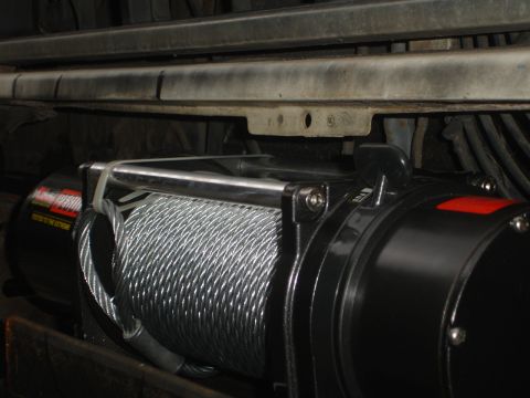 1989 Ford Bronco - Close-up of a winch and its steel cable, mounted beneath a vehicle's frame.