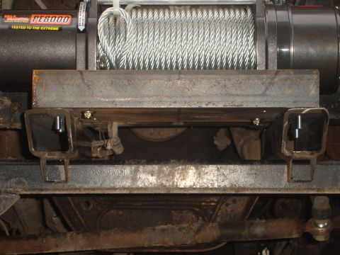 1989 Ford Bronco - Close-up view of a winch and its mounting bracket on the underside of a vehicle.
