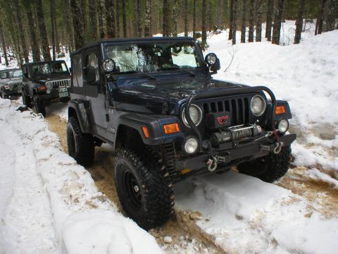 2005 Jeep Wrangler - A convoy of Jeep Wranglers navigates a snow-covered forest road during a winter excursion.