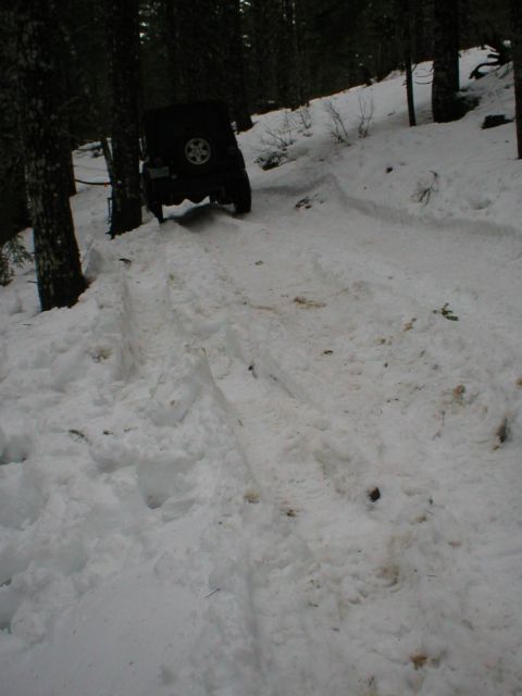 2005 Jeep Wrangler - Jeep Wrangler navigating a snow-covered forest road, showing its rear as it climbs.