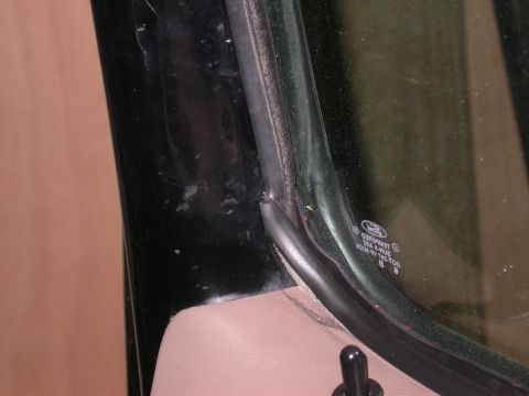 1996 Ford Bronco - Detail shot of the window seal and trim on a vehicle, with a Ford logo etched into the glass.