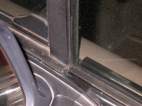 1996 Ford Bronco - Detail of a vehicle's door frame and window seal, focusing on the rubber weatherstripping and surrounding trim.