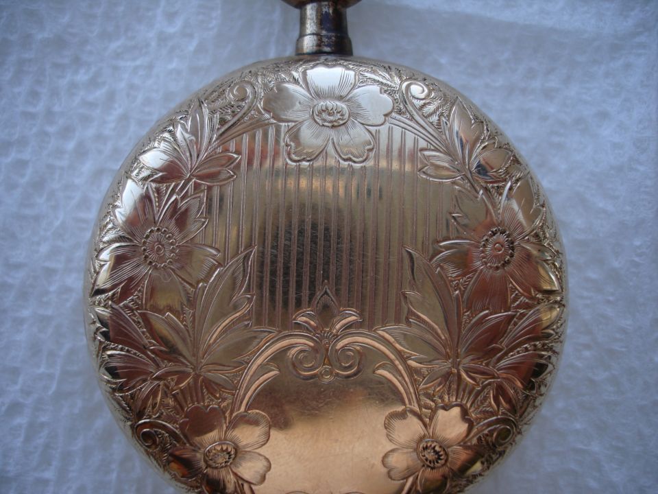 Gold pocket watch with intricate floral engravings and vertical lines