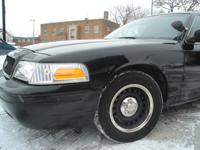 Front corner of black sedan, possibly a 2000 Ford Crown Victoria, parked on a snowy street