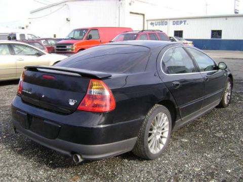 2002 Chrysler 300M - A black 2002 Chrysler 300M is parked in a lot with other vehicles and buildings in the background.