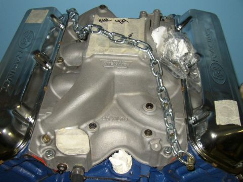 1990 Ford F-250 - Close-up of a Ford engine's intake manifold and valve covers, secured with a metal chain.