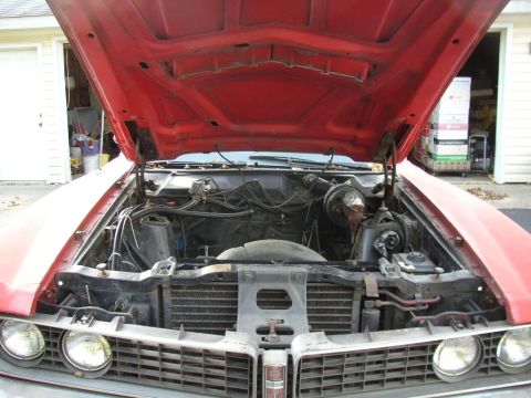 1990 Ford F-250 - Engine bay of a classic red car, likely from the early 1970s, with hood raised.