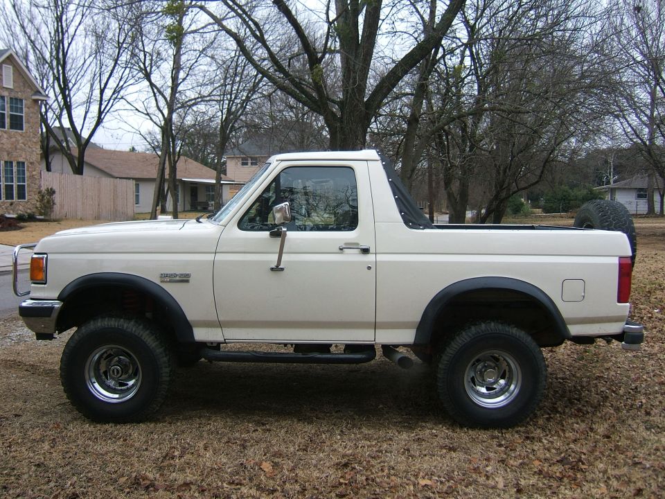 White Ford Bronco side profile with top removed, fender flares and chrome wheels