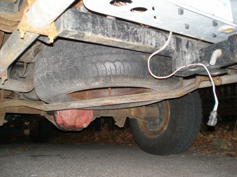 1995 Ford F-150 - The underside of a 1995 Ford F-150 reveals its spare tire, rear axle assembly, and trailer wiring harness.