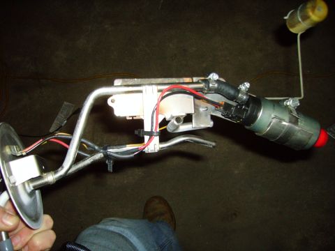 1991 Ford Bronco - A person is holding a vehicle's fuel pump assembly, which includes a float and various hoses and electrical connections.