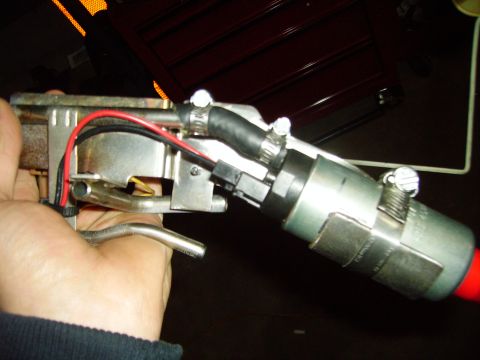 1991 Ford Bronco - A hand holds a fuel pump assembly with attached hoses and wires, with a red end visible.
