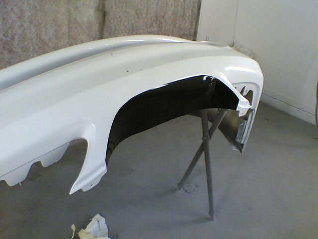 White painted front bumper cover on a metal stand in a paint shop