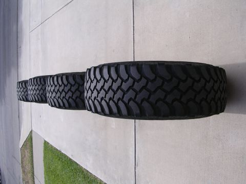1983 Ferrari Enzo - Four aggressive tread off-road tires are displayed in a row on a concrete surface.