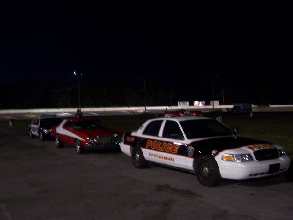 Red and white 1975 Ford Torino with a police car