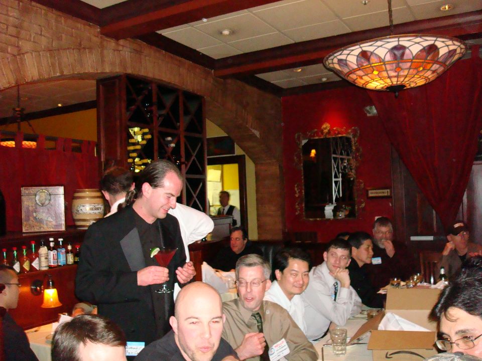 People gathered around tables in a restaurant with red walls and a stained-glass lamp