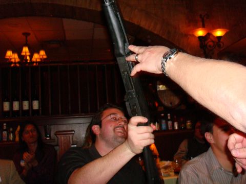 1990 Ford Bronco - A man is holding a shotgun while people are seated at tables in the background.
