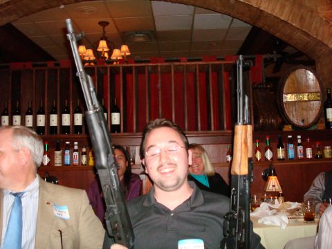 1990 Ford Bronco - A group of people are gathered at a table in what appears to be a bar or restaurant, with two individuals posing with firearms.