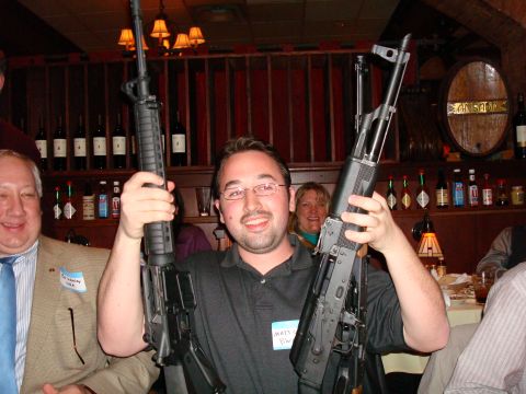 1990 Ford Bronco - Two men pose with firearms in a dimly lit room with a bar and wine bottles in the background.