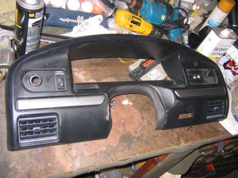 1994 Ford Bronco - A black dashboard section with air vents and a rear window control button is shown.