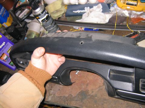 1994 Ford Bronco - A hand holds a dark gray dashboard trim piece, likely from an older vehicle.