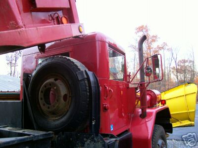 1968 Jeep CJ5 - Side view of a red dump truck equipped with a yellow snow plow, showing the cab and spare tire.