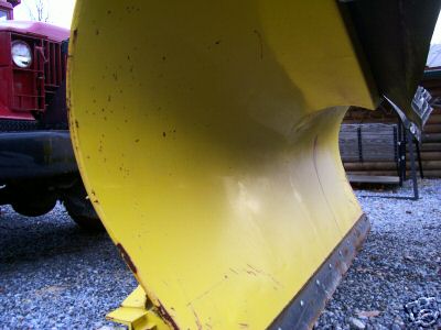 1968 Jeep CJ5 - A close-up view of a large yellow snow plow attached to the front of a red truck.
