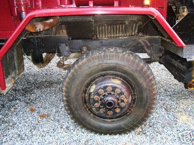 1968 Jeep CJ5 - Close-up of a red truck's chassis and wheel, showing the suspension and tire detail.