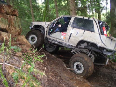 1979 Ford Bronco - This modified SUV is navigating a challenging off-road course through a wooded area.
