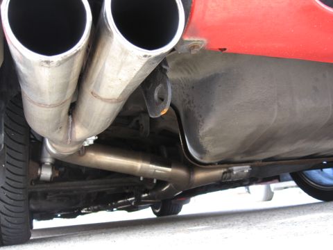 1991 Mitsubishi 3000GT - Underside view of a red vehicle's exhaust system and fuel tank.