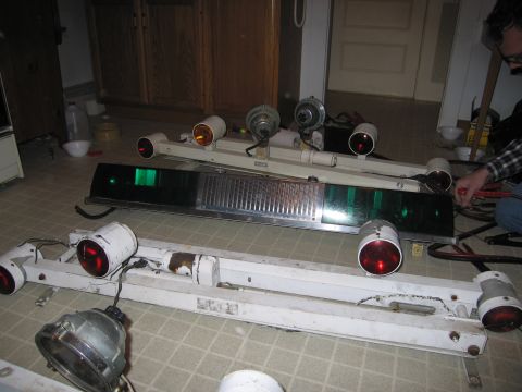 1991 Ford LTD Crown Victoria - Several vintage emergency-vehicle light bars laid out on a tile floor indoors, including white rotator bars with red and amber beacon domes…