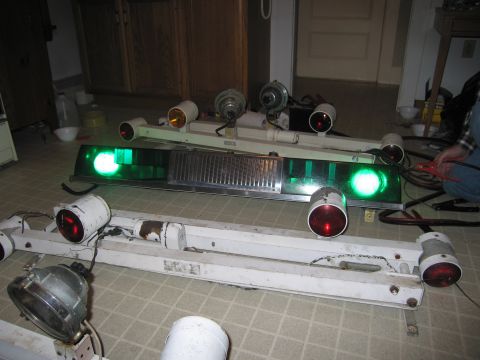 1991 Ford LTD Crown Victoria - Two police light bars, one with a chrome grille, are displayed on a tiled floor, with red and green lights visible.
