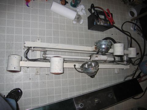 1991 Ford LTD Crown Victoria - A collection of miscellaneous items including a light fixture, car battery, and jumper cables are laid out on a tiled floor.