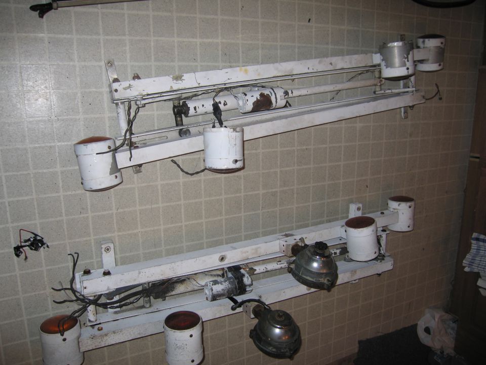 Two white light fixtures with orange lenses mounted on white bars against a tiled wall