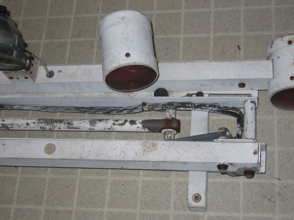 White police light bar with red lights and wiring, mounted on a tiled wall