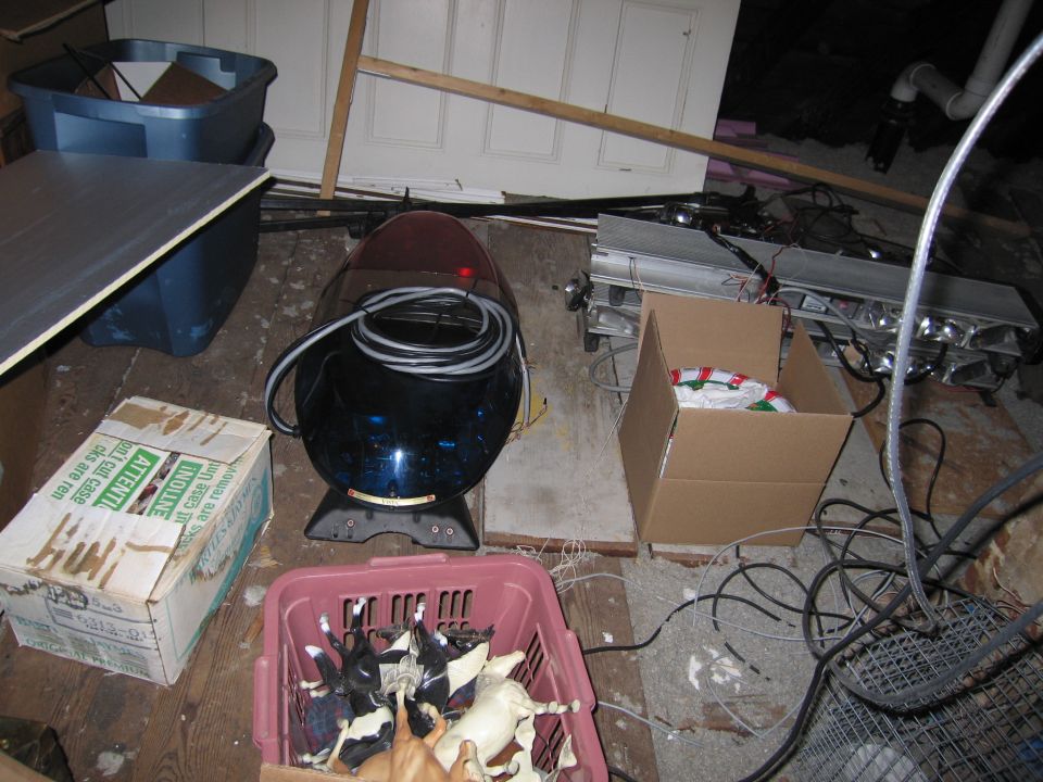Blue police light bar with cord, box of toy horses in a pink basket, and a cardboard box with text