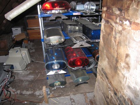 1991 Ford LTD Crown Victoria - Various police light bars and other equipment are stored on shelves in a dusty attic space.