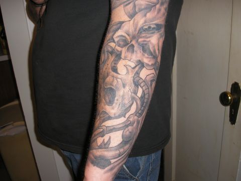 1995 Ford Bronco - A close-up view of a grey-toned tattoo a skull and mechanical elements on a person's arm.