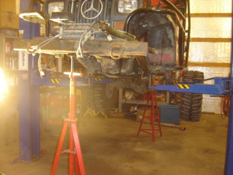 1992 Ford Bronco - A vehicle is raised on a lift in a workshop, with its front end disassembled for maintenance.