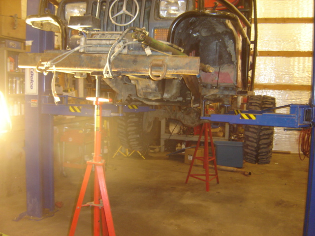 Off-road vehicle on a lift in a garage, front end visible, undergoing repairs