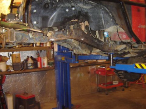 1992 Ford Bronco - The underside of a vehicle is suspended on a hydraulic lift in a workshop environment.