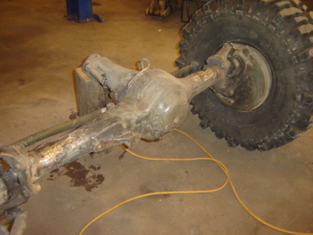 Rear axle assembly and tire, likely from a truck or SUV, resting on a shop floor
