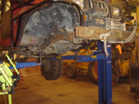 1992 Ford Bronco - The underside of a vehicle is shown elevated on a lift, revealing its chassis and suspension system.