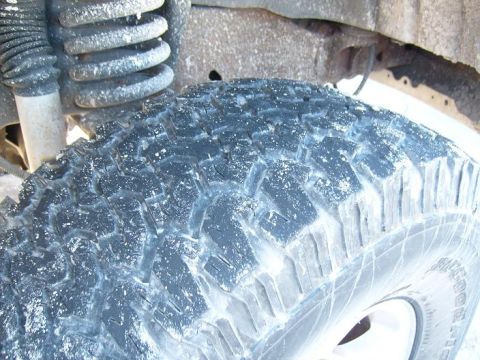 1995 Ford C-150 (Centurion Conversions) - Detail shot of a vehicle's tire and suspension system, covered in a light dusting of snow.