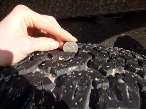1995 Ford C-150 (Centurion Conversions) - Checking tire tread depth with a coin.