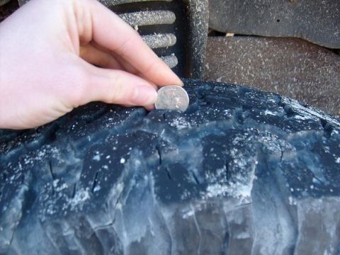 1995 Ford C-150 (Centurion Conversions) - Tire tread depth is measured with a quarter, indicating significant wear.