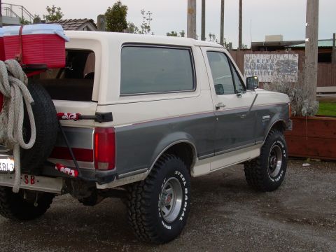 1991 Ford Bronco - This 1991 Ford Bronco features a two-tone paint scheme and a rear-mounted spare tire, seen from a three-quarter rear perspective.
