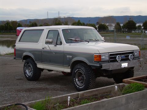 1991 Ford Bronco - This 1991 Ford Bronco is shown from a three-quarter front view, highlighting its two-tone paint and off-road tires.
