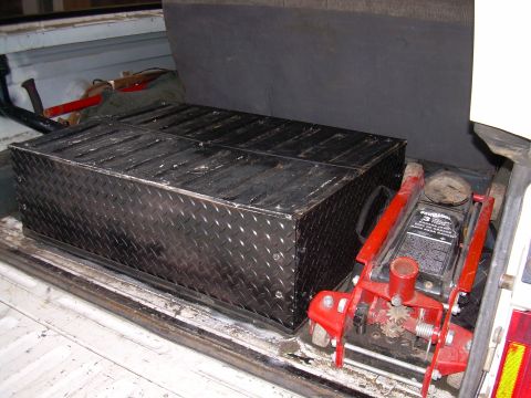 1991 Ford Bronco - A diamond plate toolbox and a red hydraulic jack are stored in the cargo area of a vehicle.
