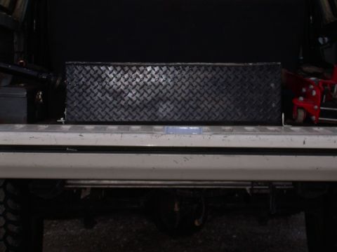 1991 Ford Bronco - A toolbox is stored in the cargo area of a vehicle, with a jack nearby.