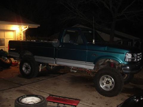 1996 Ford F-150 - A teal 1996 Ford F-150 pickup truck is shown with a lifted suspension and aftermarket wheels.